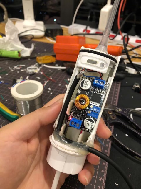 The water flosser opened up, with the converter module wired in where the battery used to be